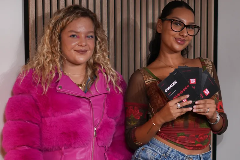 Deux invitées tenant des cartes imprimées dans un studio podcast
