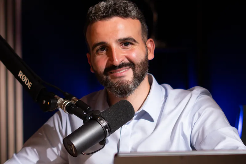 Invité barbu en chemise bleu clair au micro dans un studio à Genève