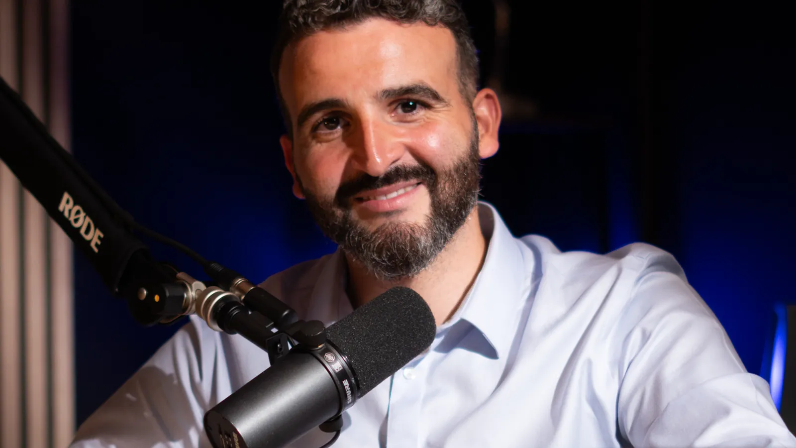 Invité barbu en chemise bleu clair au micro dans un studio à Genève