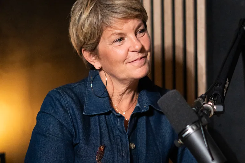 Femme aux cheveux courts en chemise en jean au micro dans un studio podcast