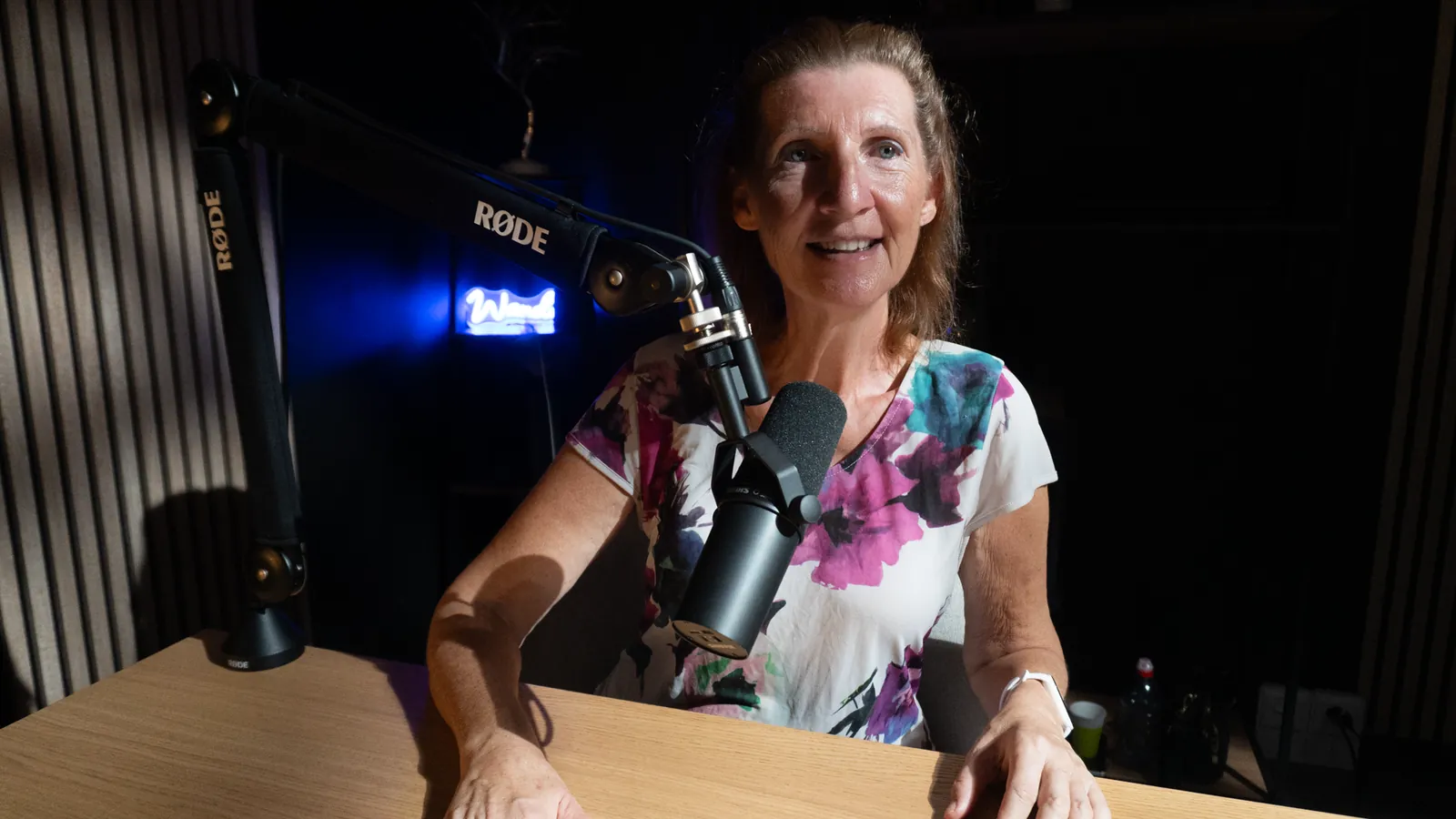 Invitée au micro dans un studio podcast éclairé en bleu à Genève
