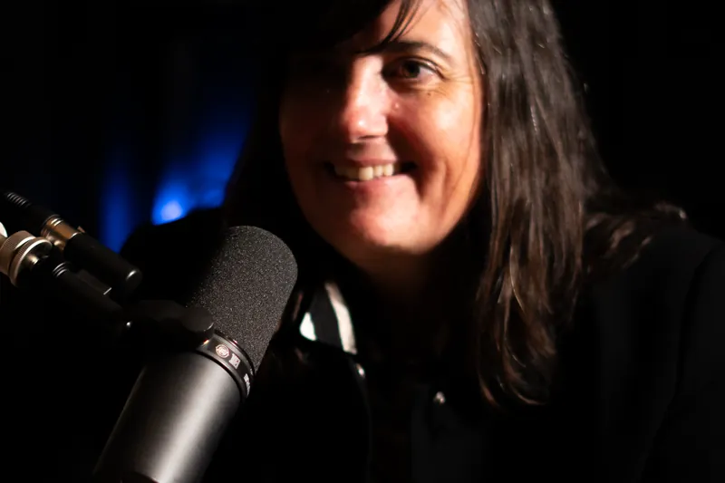 Invitée souriante au micro dans une ambiance tamisée de studio