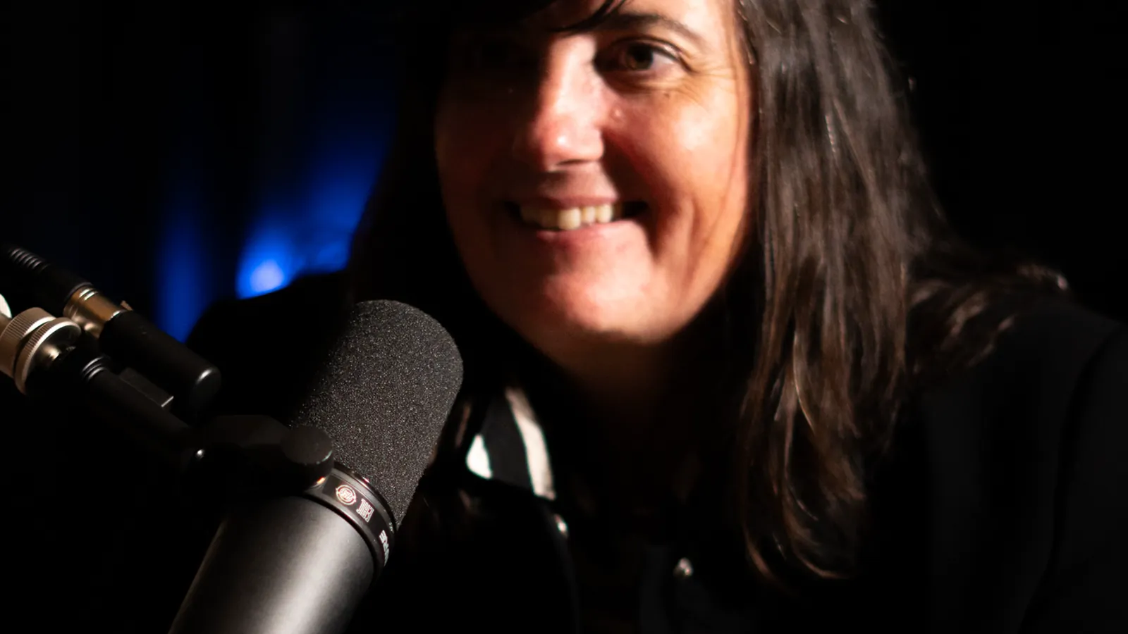 Invitée souriante au micro dans une ambiance tamisée de studio