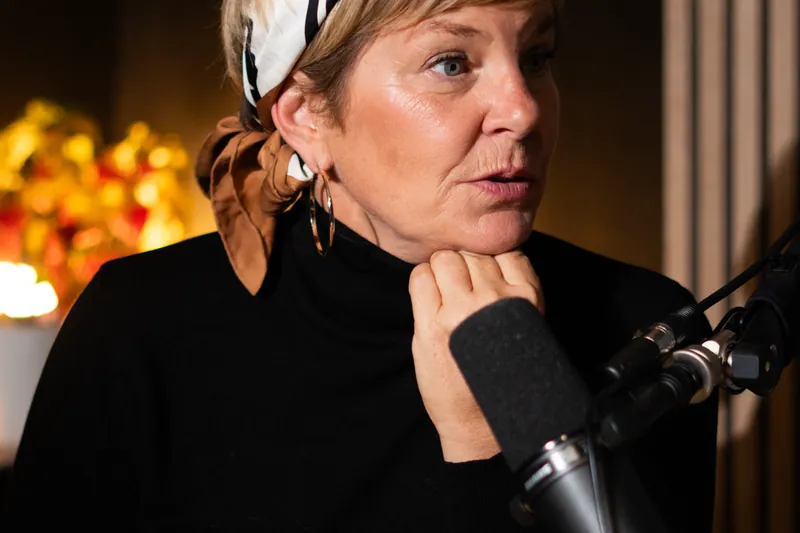 Commerçante portant un foulard, la main sous le menton, au micro dans un studio