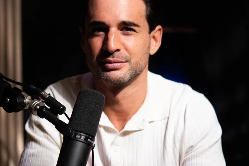 Homme en polo blanc au micro, éclairage sombre de studio