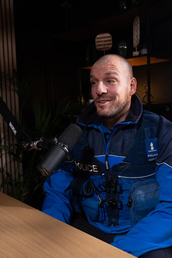 Policier genevois en uniforme, souriant derrière le micro