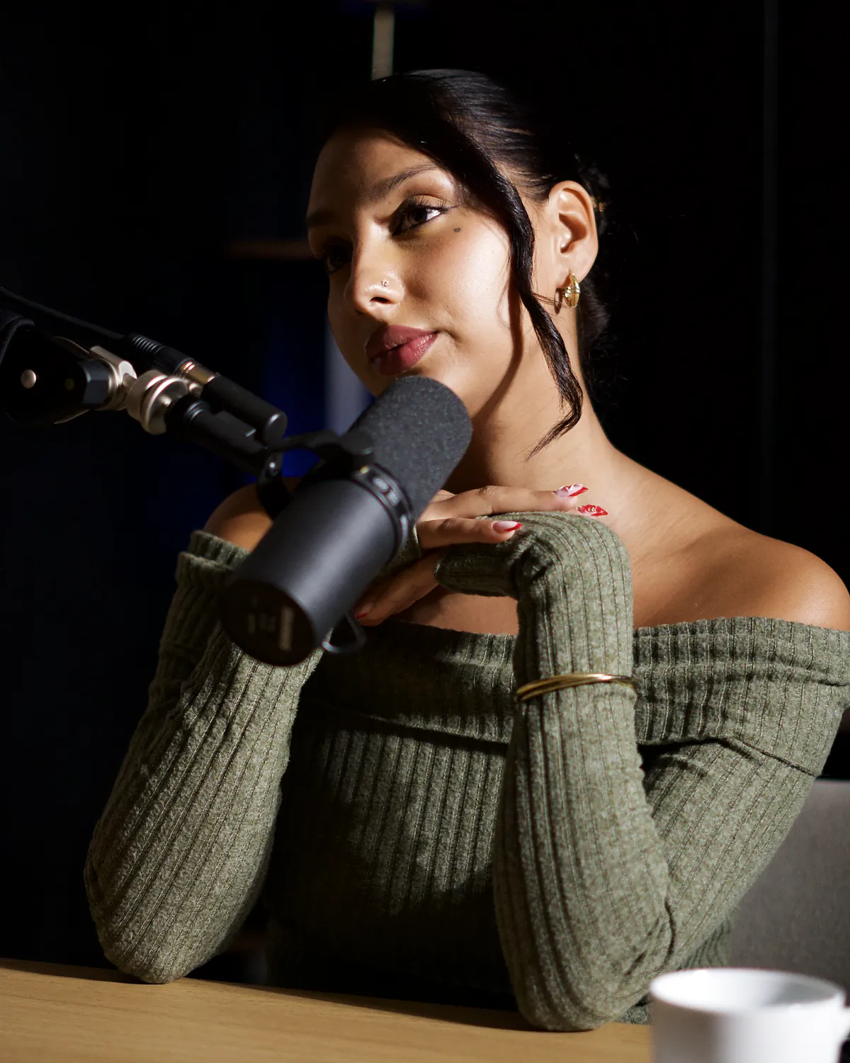 Anjou au Studio Rhône, le menton posé sur les mains derrière le micro, en pull vert