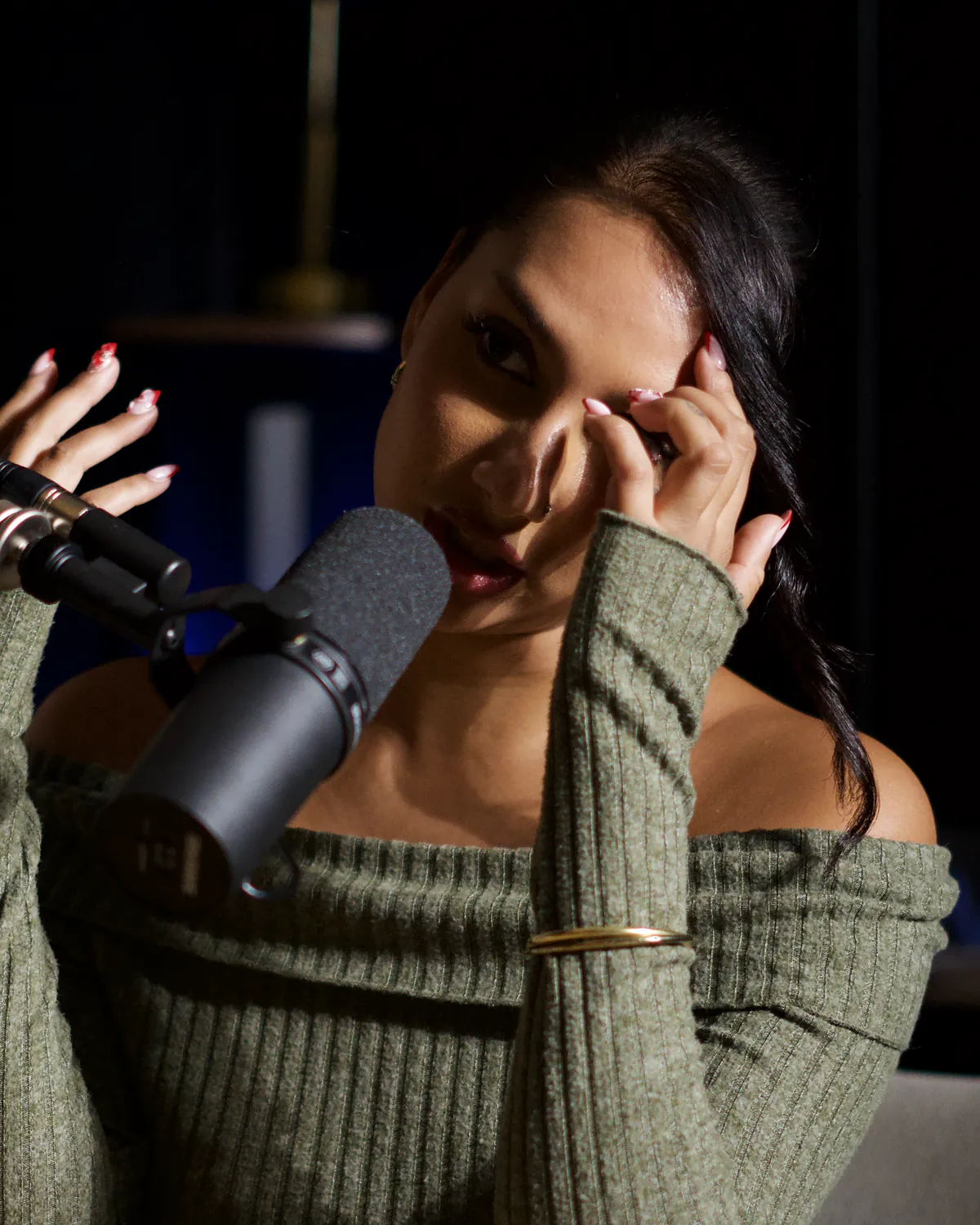Anjou rit au Studio Rhône, une main dans les cheveux, pendant le tournage du podcast